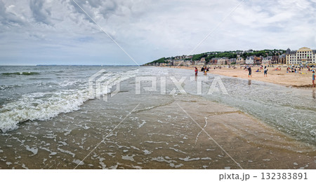 Trouville-sur-Mer, Normandy, France - May 31, 2025: panoramic view of the wide sandy beach and the ocean under an overcast sky with the charming french town in the background Trouville-sur-Mer, Normandy, France - May 31, 2025: panoramic view of the wide sandy beach and the ocean under an overcast sky with the charming french town in the background 132383891