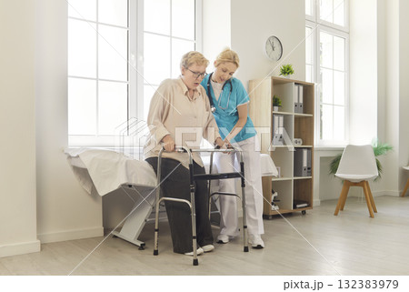 Nurse helping senior patient safe walking, using walker in medical clinic 132383979