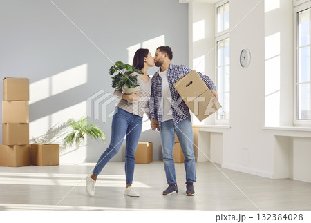 Young beautiful couple with moving boxes kissing in new home 132384028
