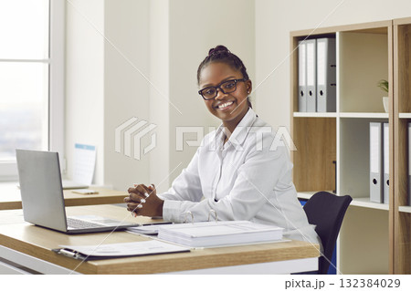 Portrait of happy young African American businesswoman at office desk with laptop 132384029