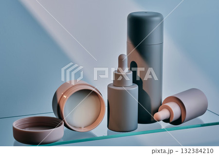 A composition of cosmetic care products on a glass shelf. 132384210