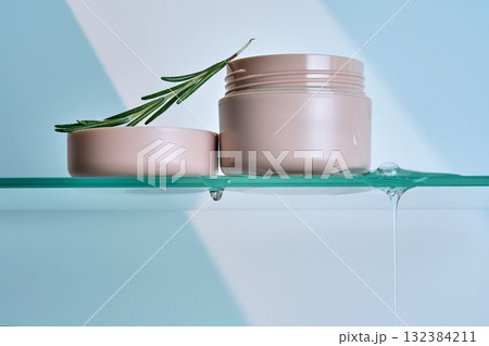 A jar of rosemary cream on the glass shelf of the bathroom. A jar of rosemary cream on the glass shelf of the bathroom. 132384211