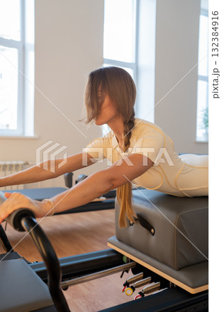 Woman doing Swan exercise on Pilates Reformer for the chest and back muscles, focusing on flexibility, strength, and control with determination Woman doing Swan exercise on Pilates Reformer for the chest and back muscles, focusing on flexibility, strength, and control with determination 132384916