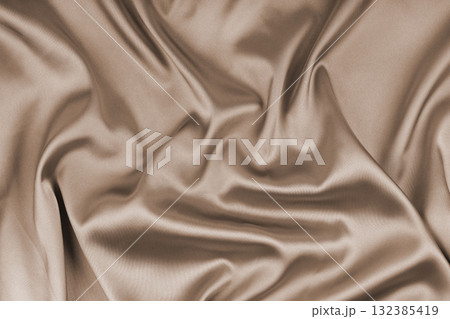 Crumpled, wrinkled beige colored glossy silk satin texture. Shiny smooth fabric with soft folds Crumpled, wrinkled beige colored glossy silk satin texture. Shiny smooth fabric with soft folds 132385419