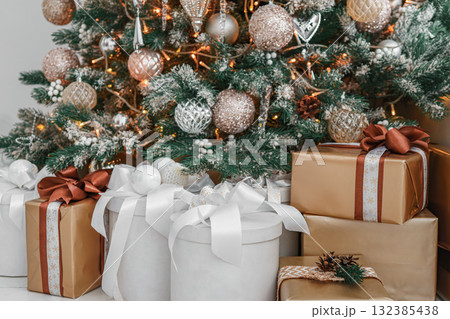 Beautiful Christmas tree decorated with festive ornaments and bright lights and wrapped gift boxes 132385438