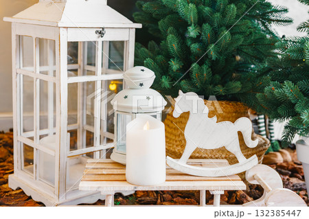 Cozy indoor setting, composition white lantern and wooden decorations on Christmas trees background 132385447