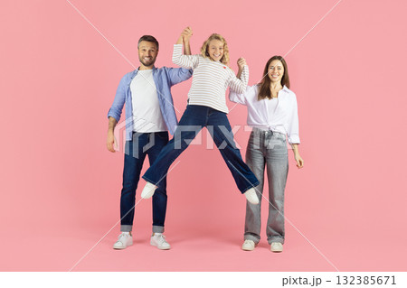 Happy parents lifting daughter in air in studio, playful family moment Happy parents lifting daughter in air in studio, playful family moment 132385671