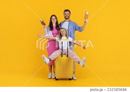 Excited family with suitcases and passports having fun on yellow studio background 132385686