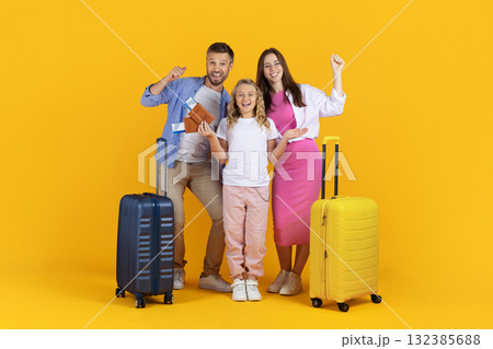 Excited family with passports and suitcases in studio on yellow background 132385688