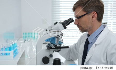 Medical scientist wearing gloves using microscope analyzing samples in modern laboratory doing scientific research. Medicine, healthcare and science concept 132386546