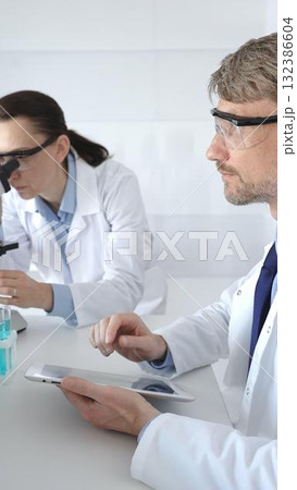 Medical researchers examine laboratory samples under a microscope and digital tablet during a collaborative scientific study. Medicine and science, teamwork concept Medical researchers examine laboratory samples under a microscope and digital tablet during a collaborative scientific study. Medicine and science, teamwork concept 132386604
