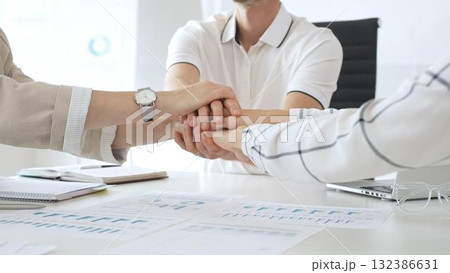 Business people team joining hands over workplace documents, symbolizing collaborative spirit and shared workplace success, close up view Business people team joining hands over workplace documents, symbolizing collaborative spirit and shared workplace success, close up view 132386631