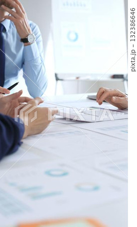 Business team meeting with charts and documents on desk discussing financial strategy, planning corporate growth, analyzing market data and performance reports 132386646