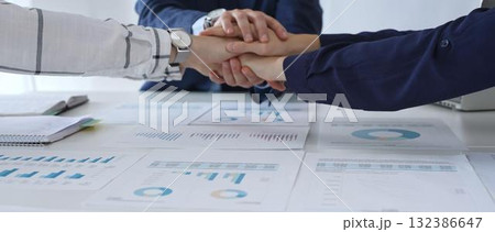 Teamwork and business collaboration with colleagues joining hands over financial charts, symbolizing unity, partnership, success, and strategic corporate planning Teamwork and business collaboration with colleagues joining hands over financial charts, symbolizing unity, partnership, success, and strategic corporate planning 132386647
