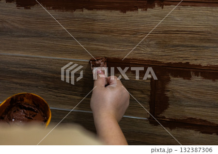 Hand-applying brown grout to the joints of ceramic floor tiles during a home renovation Close-up of a skilled craftsman or professional refinishing and refinishing flooring in a residential interior. Hand-applying brown grout to the joints of ceramic floor tiles during a home renovation Close-up of a skilled craftsman or professional refinishing and refinishing flooring in a residential interior. 132387306