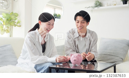 貯金箱にお金を入れるアジア人のカップル 132387633