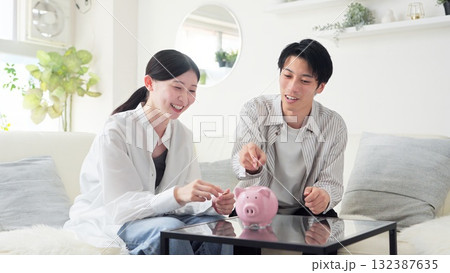 貯金箱にお金を入れるアジア人のカップル 132387635