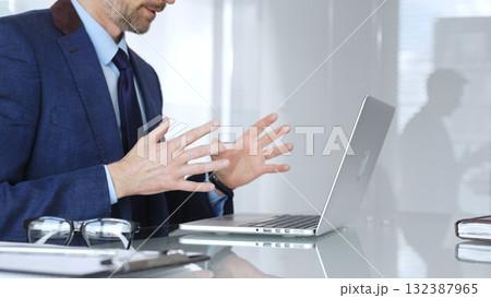 Businessman having a video conference, gesturing during an online business meeting or remote negotiation. Business people concept Businessman having a video conference, gesturing during an online business meeting or remote negotiation. Business people concept 132387965