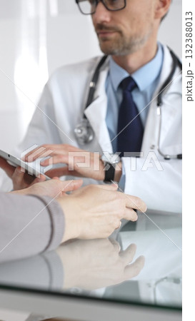 Male doctor consulting female patient, discussing diagnosis and medical history with digital tablet in clinic. Medicine and health care Male doctor consulting female patient, discussing diagnosis and medical history with digital tablet in clinic. Medicine and health care 132388013