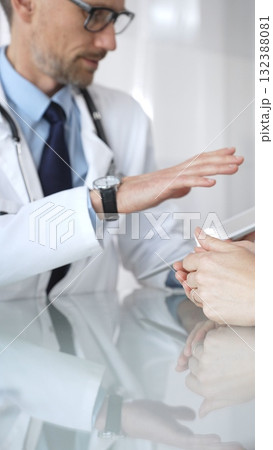 Male doctor consulting female patient, discussing diagnosis and medical history with digital tablet in clinic. Medicine and health care 132388081