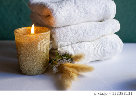 Golden candle, white towels, and wildflowers in an aesthetic arrangement.Horizontal shot. Natural light Golden candle, white towels, and wildflowers in an aesthetic arrangement.Horizontal shot. Natural light 132388131