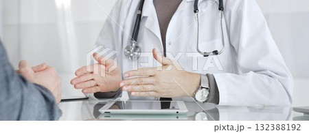 Doctor consulting patient, discussing diagnosis, using digital tablet in modern medical clinic. Medicine and health care 132388192