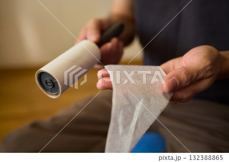 A person effectively uses a lint roller to remove pet hair and debris from clothes and furniture 132388865