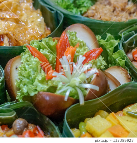 Pindang eggs (Indonesian braised eggs) served with chili garnish and lettuce in a banana leaf-lined box. Authentic Indonesian cuisine with eco-friendly presentation 132389925