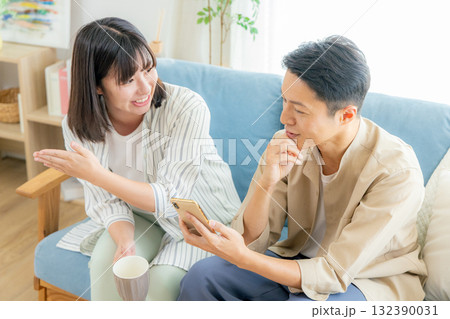 リビングでスマホを見る夫婦 リビングでスマホを見る夫婦 132390031