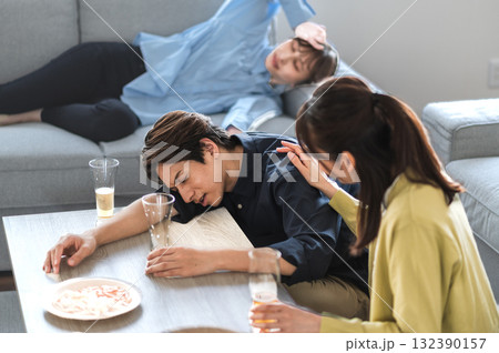 酔い潰れた男性に声をかける女性 132390157