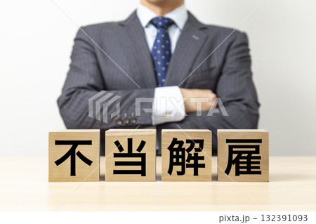「不当解雇」と書かれたブロックと腕組みをするビジネスマン 「不当解雇」と書かれたブロックと腕組みをするビジネスマン 132391093