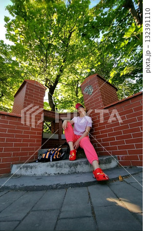 A person resting on a bench under an old, weathered brick archway, with a vintage hanging lantern in the foreground. 132391110