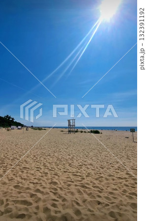 A simple, elevated white wooden structure used by lifeguards stands on the sand overlooking the Baltic Sea. 132391192