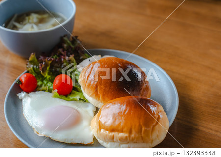 ロールパンと目玉焼き、サラダとスープを添えた洋風の朝食 ロールパンと目玉焼き、サラダとスープを添えた洋風の朝食 132393338