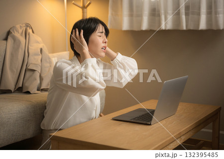 仕事が終わらなくて結局家で仕事する女性 夜の部屋でパソコンを見て頭を抱える女性のクローズアップ 仕事が終わらなくて結局家で仕事する女性 夜の部屋でパソコンを見て頭を抱える女性のクローズアップ 132395485