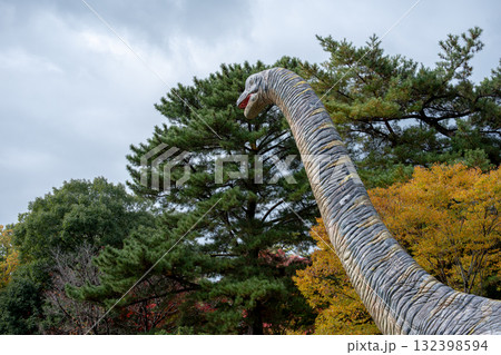 恐竜の像と秋の木々 132398594
