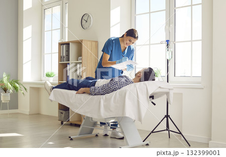 Male patient lying on couch in medical clinic and receiving IV drip infusion and vitamin therapy. 132399001