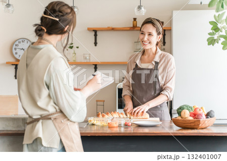 料理教室・クッキングスクールで料理を教える講師の女性と生徒の女性 132401007