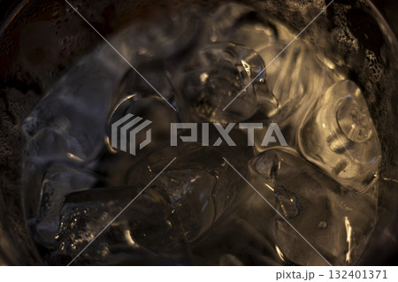 Melting Ice Cubes In Water Glass, refreshing moment perfect for beverage ads, summer lifestyle campaigns, hydration storytelling, and cooling drink promotions. 132401371