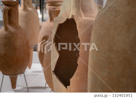 Vintage pottery collection, with focus on hollow, damaged pot. Set exhibits historical significance, varied shapes and sizes in earthy hues 132401951