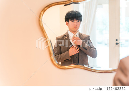 結婚式場のブライズルームで鏡,支度をするスーツ,タキシード姿の新郎 132402282