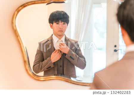 結婚式場のブライズルームで鏡,支度をするスーツ,タキシード姿の新郎 132402283