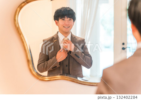 結婚式場のブライズルームで鏡,支度をするスーツ,タキシード姿の新郎 132402284