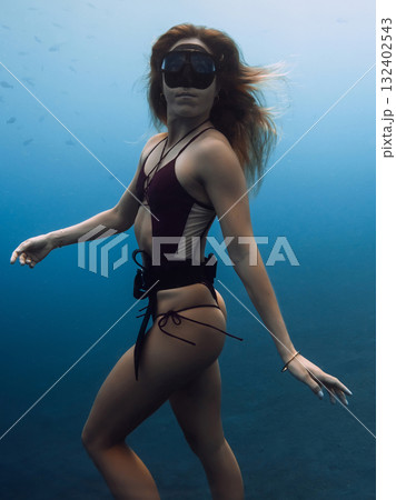 Portrait of woman freediver underwater in blue sea Portrait of woman freediver underwater in blue sea 132402543