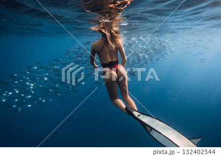 Woman freediver swimming with school of tuna fish in blue sea Woman freediver swimming with school of tuna fish in blue sea 132402544