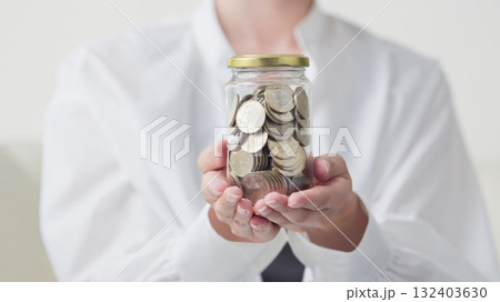 お金が入った瓶を持つアジア人女性の手元 132403630