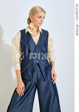 Elegant casual outfit featuring a blue vest and wide-leg pants against a plain backdrop 132403733
