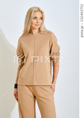 Woman in beige outfit poses gracefully in a bright studio setting Woman in beige outfit poses gracefully in a bright studio setting 132403752