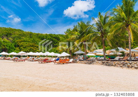 luxury resort with sun beds and umbrellas under palm trees on beach by the sea in summer. Landscape with view of shore coast by the ocean. Tropical island beach. Travel vacation destination in Asia 132403808