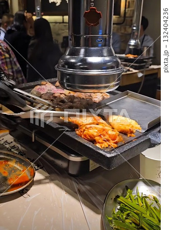 Cooking Korean BBQ on a Tabletop Grill, Featuring Thinly Sliced Raw Beef and Tongs Flipping Meat... Cooking Korean BBQ on a Tabletop Grill, Featuring Thinly Sliced Raw Beef and Tongs Flipping Meat... 132404236